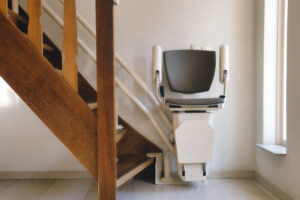 A Compact Stair Lift is Mounted Beside a Wooden Staircase in a Bright Hallway.